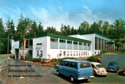Farbfoto aus den 1960er-Jahren: Schwimmhallen-Komplex mit Flachdach, beschriftet mit „Gesamtansicht der Schwimmhalle am Rande des Felixwaldes“.