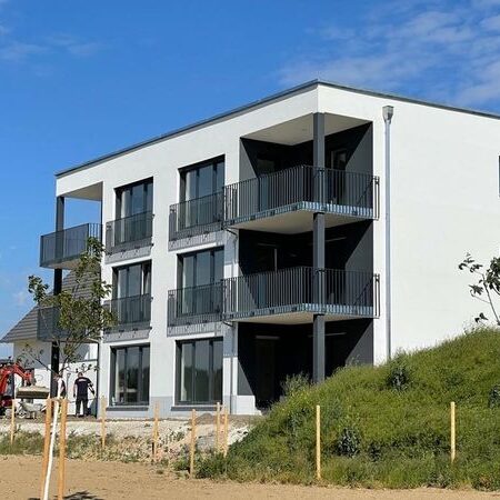 Neubau eines modernen Wohngebäudes mit drei Etagen, Balkonen und großflächigen Fenstern.