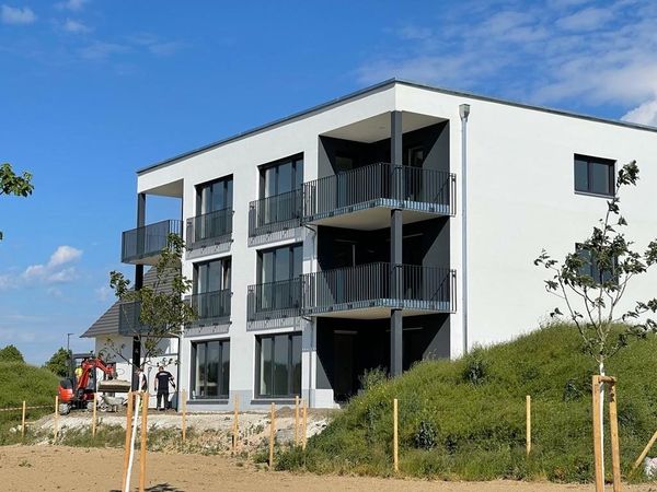 Neubau eines modernen Wohngebäudes mit drei Etagen, Balkonen und großflächigen Fenstern.