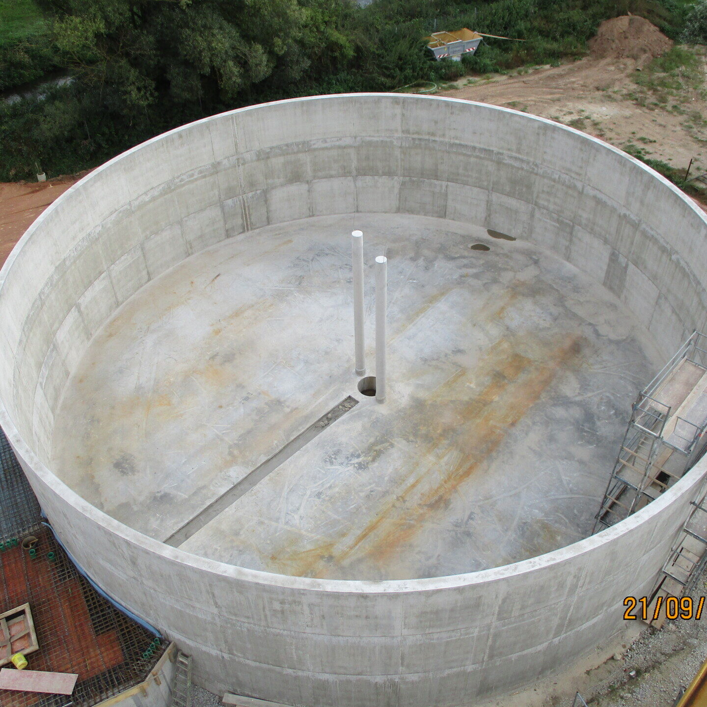Innenaufnahme einer modernen Baustelle mit Betonwänden, Baustellenleuchten und einem Rohbau-Fensterausschnitt.