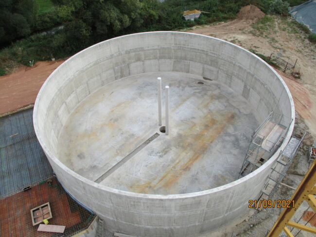 Innenaufnahme einer modernen Baustelle mit Betonwänden, Baustellenleuchten und einem Rohbau-Fensterausschnitt.