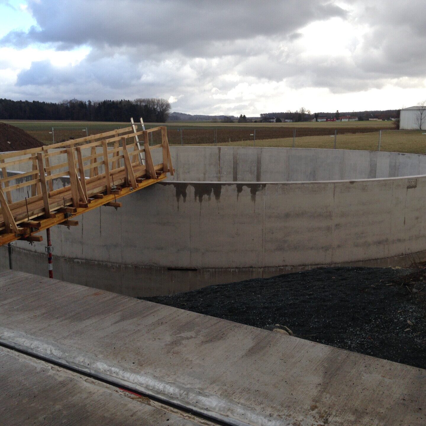 Gebäude mit Klinkerfassade und moderner Architektur, umgeben von bepflanzten Grünflächen und Wegen.