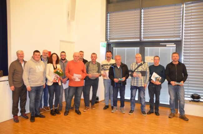 Ehrungen 2023 Eine Gruppe von etwa 15 Personen posiert in einem Innenraum mit Urkunden, eine Frau hält einen Blumenstrauß.